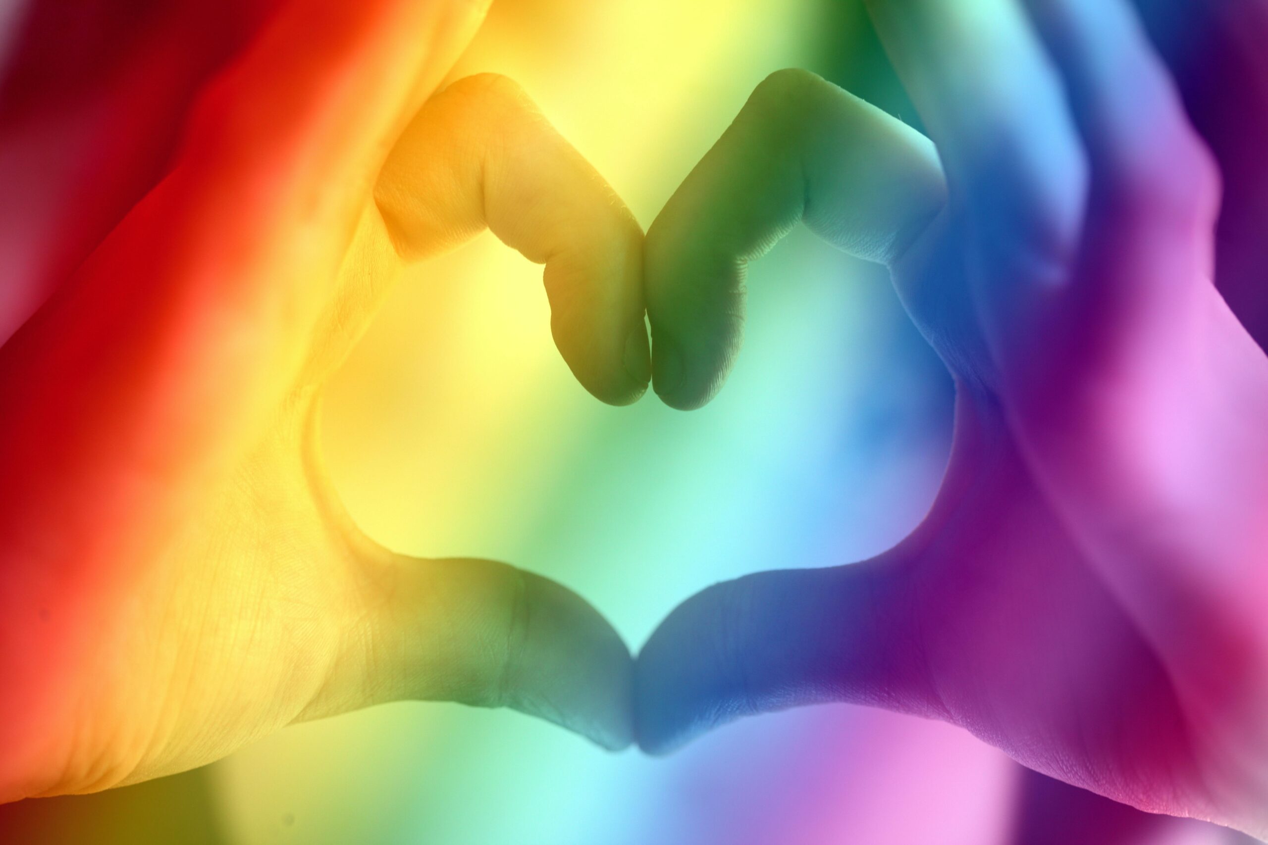 Hände die ein Herz bilden in Regenbogenfarbe